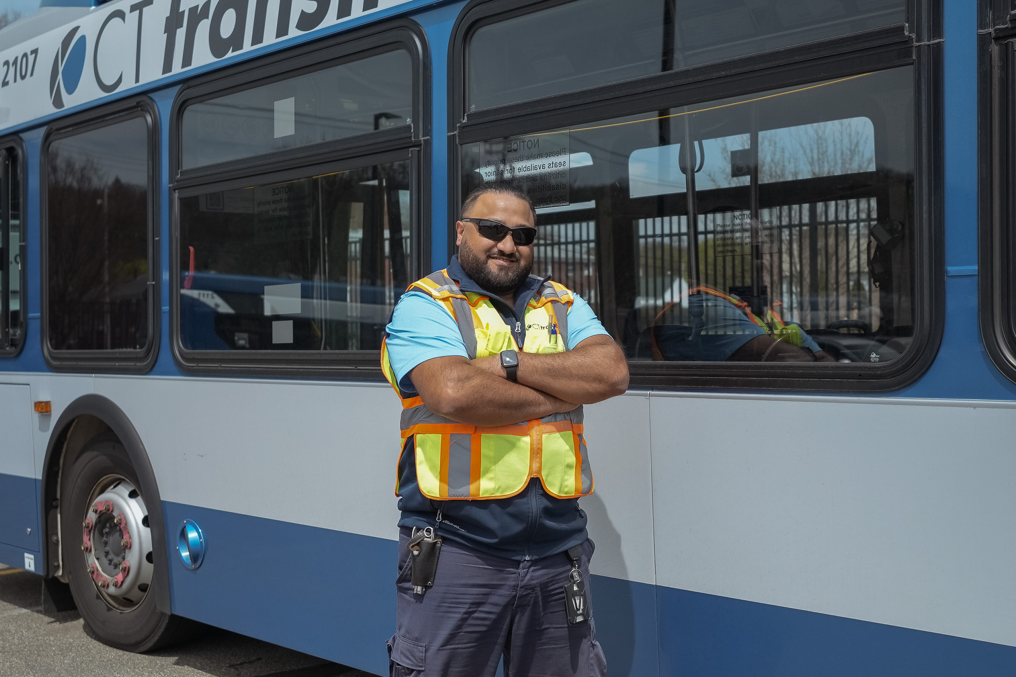 Bus operator smiling in front of a bus